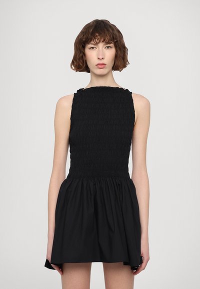 Sort kjole med smocked liv og flagrende skørt. Uden ærmer med rund halsudskæring og tekstureret stof. Enkel og elegant silhuet.