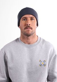 Bonnet en tricot bleu marine et sweat-shirt gris avec motif floral bleu et jaune sur la poitrine. Texture lisse, forme ajustée, design décontracté.