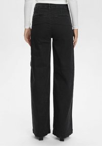 Pantalon noir à jambes larges en tissu lisse et résistant. Comprend deux poches arrière et un ourlet retroussé. Design simple et épuré avec une coupe décontractée.