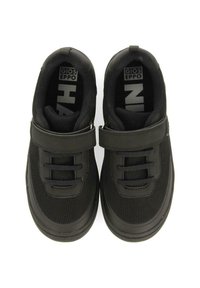 Zapatillas negras con tejido de malla, suelas de goma y correa de velcro. Las características incluyen cordones elásticos y patrones de logotipos en el interior.