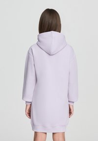 Jasnofioletowa sukienka dresowa z kapturem, z długimi rękawami, ribbowanymi mankietami i luźnym krojem, wykonana z miękkiego, teksturowanego materiału.