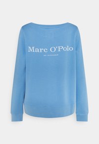 Sudadera azul hecha de tela suave, con un cuello redondo y puños de canalé. La parte posterior muestra texto en blanco: "Marc O'Polo EST. IN STOCKHOLM."