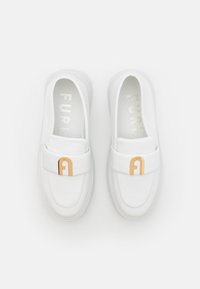 Scarpe slip-on in pelle bianca con texture liscia, dotate di un accento logo in tonalità oro sulla fascia e una suola sagomata.