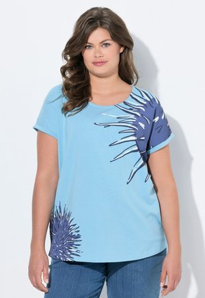 Maglietta azzurra chiara con un design grafico spigoloso blu scuro sul lato sinistro. Maniche corte con scollatura rotonda. Tessuto morbido e casual.