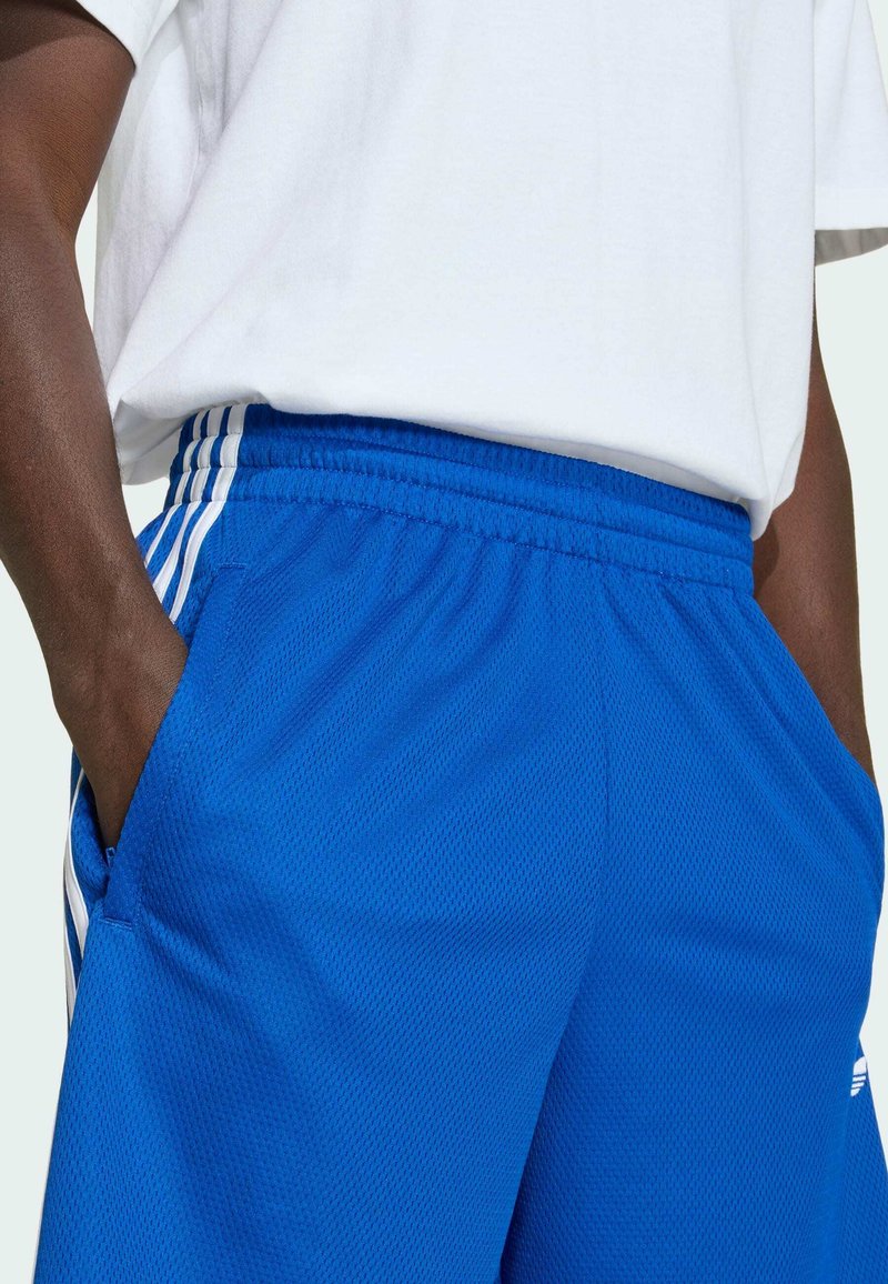 Shorts de sport bleus en tissu mesh, avec des bandes blanches sur les côtés et une taille élastique équipée de poches.