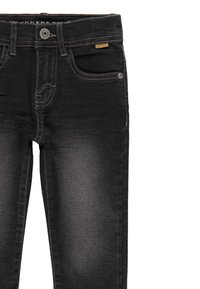 Jeans de mezclilla negra con corte slim, que cuentan con cinco bolsillos, costuras ligeras y cierre de botón. La tela presenta un desvanecimiento sutil.