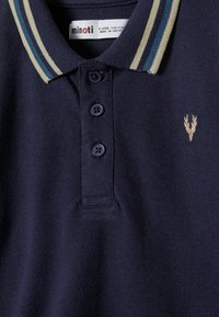 Temno modra polo majica s tremi gumbi, črtastim ovratnikom, vezenim logotipom jelena in znamko Minoti, namenjena otrokom, starim 5-6 let.