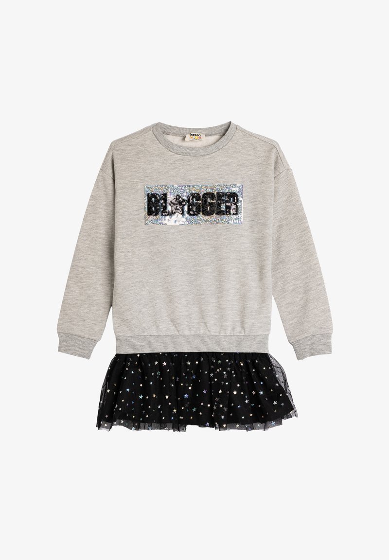 Sweatshirt en coton gris avec un patch "BLOGGER" en sequins noirs. Présente une jupe en tulle noire ornée de motifs d'étoiles métalliques.