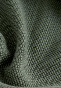 Pletená látka v tlumené zelené barvě s texturovaným žebernatým vzorem. Povrch působí měkce a mírně pruží.