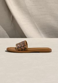 Sandale à glissière beige avec une empeigne en cuir à motifs dans des tons de marron, une semelle intérieure lisse et une semelle en caoutchouc profilée basse.