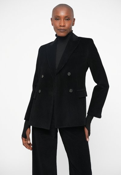 Blazer duplo em grosso corduroy preto com lapelas erguidas e dois bolsos frontais. Apresenta textura canelada e detalhes com botões.