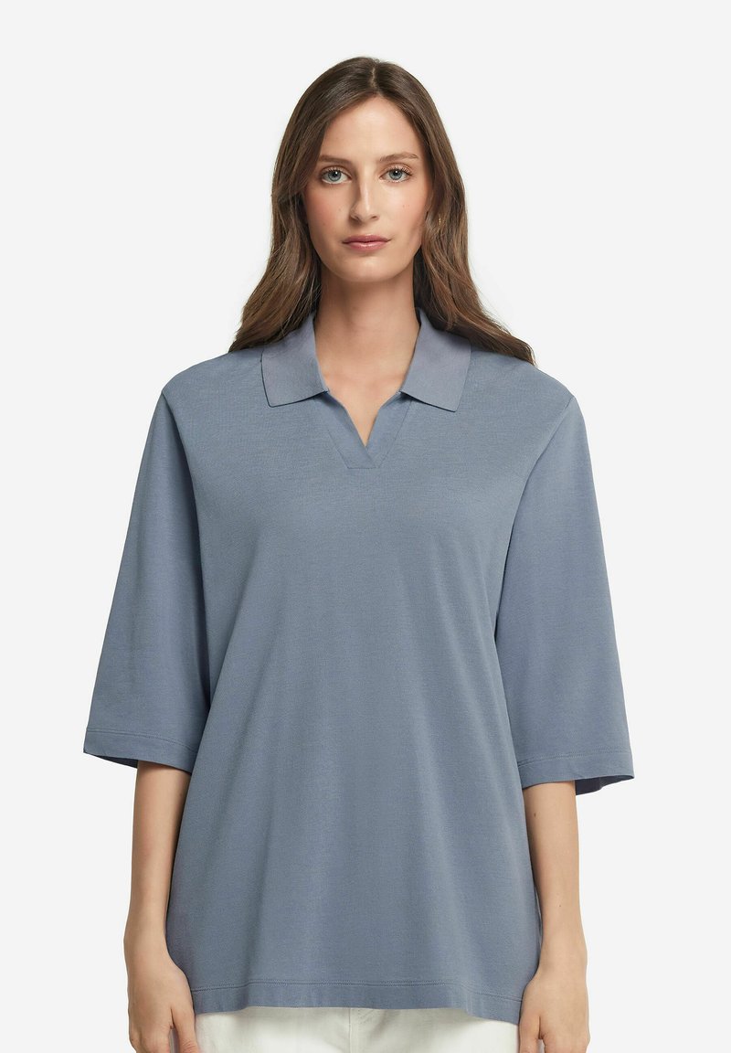 Ljusblå polo med v-ringning, kort ärm och mjuk textur, med ett subtilt mönster och en klassisk kragsdesign.