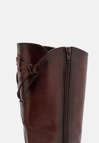 Brune lær ankle støvler med rund topp, glidelås på siden og justerbar stropp på siden for passform. Glatt tekstur.