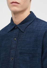 Marineblauwe button-up shirt van textuurstof met een spread collar, voorkant met knopen en een borstzak. Voorzien van zwarte knopen.