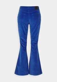 Calças de veludo cotelê azuis com uma textura suave, apresentando dois bolsos traseiros e um rótulo da marca preto na cintura.