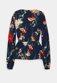 Blusa floral azul marinho com mangas longas, apresentando uma cintura peplum. Flores em vermelho, branco e verde contra um fundo escuro. Textura de tecido suave.