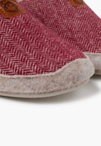 Sněhule s červeno-krémovým vzorem v rybí kosti, vyrobené z měkké vlny, s koženou hnědou nášivkou. Zaoblená špička a lehká podešev.