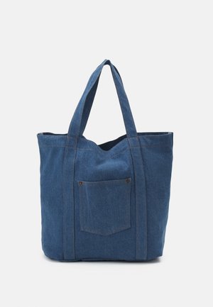 Grote blauwe denimtas met dubbele schouderbanden en een klein voorvakje met klinknageldetails.