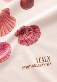 Tela de algodón con estampados de conchas en color rosa sobre un fondo crema, con "ITALIA" y "MAR MEDITERRÁNEO" en letras doradas.