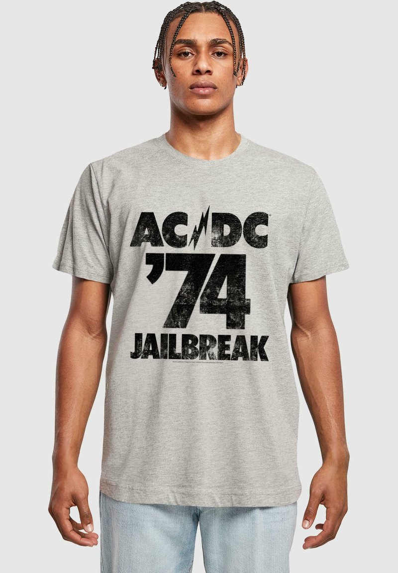 Sivá bavlnená tričko s výraznou čiernou grafikou a textom "AC/DC '74 JAILBREAK" a dizajnom blesku, okrúhly výstrih a krátke rukávy.