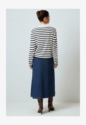 Maglione a maniche lunghe a righe in crema e blu navy, abbinato a una gonna di jeans blu e stivali con tacco marroni. La vista posteriore mette in evidenza forme e texture.