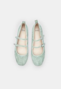 Balerinke iz zelenega semiša v svetleči mentolni barvi z dvema nastavljivima zaponkama, zaobljenimi prsti in gladko notranjostjo. Ime blagovne znamke je vidno znotraj.