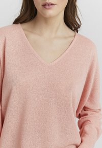 Rosa gestrickter Pullover mit V-Ausschnitt und langen Ärmeln, aus strukturiertem Stoff und in lässiger Passform.