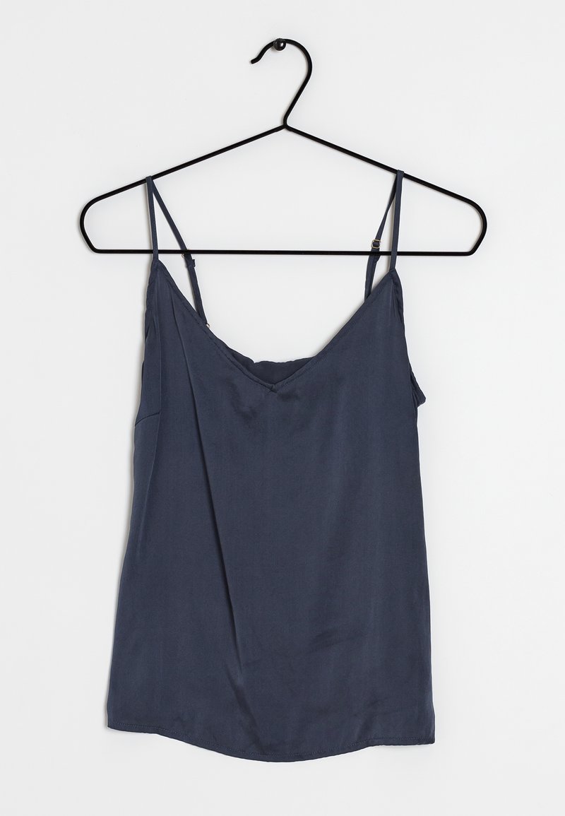 Camisole en soie bleu marine avec fines bretelles réglables, col en V et texture douce. Suspendue à un cintre en métal noir.