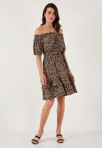 Off-the-shoulder leopard print dress in beige and brown, with puffed sleeves, cinched waist, and tiered ruffled skirt.
