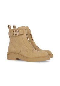 Béžové semišové kotníkové boty s hladkým povrchem, mají dekorativní kovový emblém, přední zipy a nízký blokový podpatek.