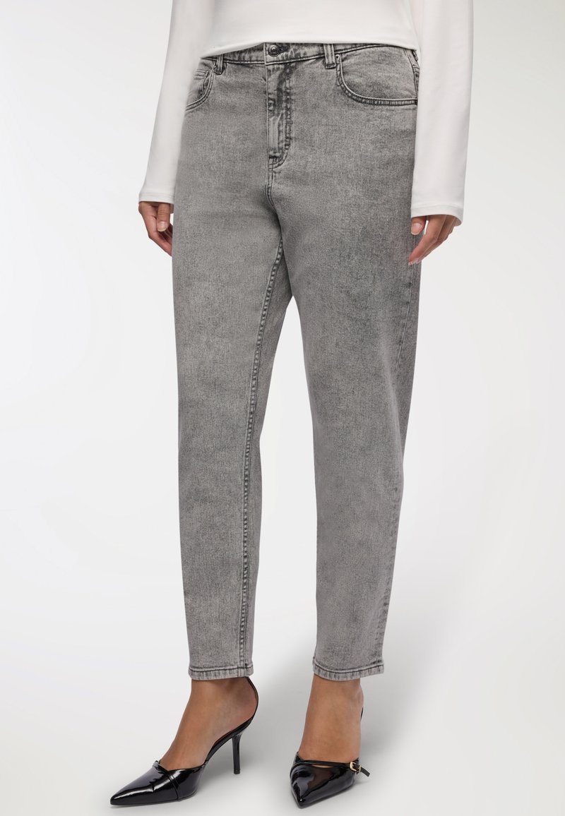 Jeans in denim grigio con design a gamba dritta, dotati di tasche frontali e una texture sbiadita. Abbinati a tacchi neri a punta.