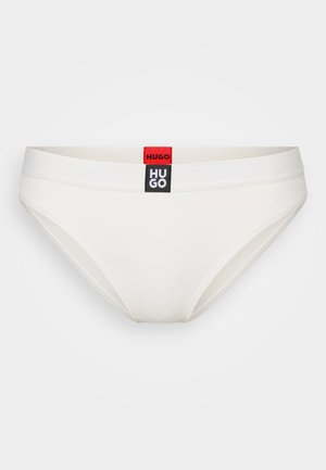 Cueca branca de algodão com uma textura canelada. Apresenta um rótulo de logotipo preto e vermelho na cintura. Forma e design clássicos.