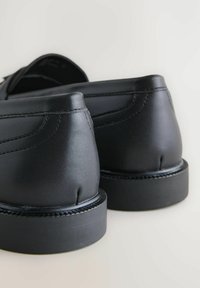 Sorte lædersko med en glat finish og rund hæl, der har syninger og gummisåler. Designet til formelt brug.
