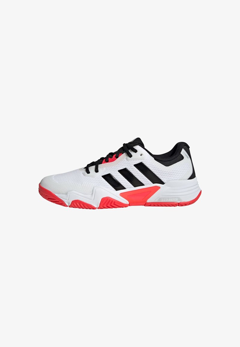 White athletic shoe with black accents, featuring three black stripes, a textured upper, and a red rubber sole with zigzag pattern.