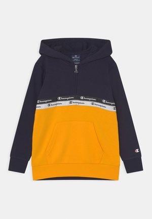 Marineblå og gul hættetrøje med frontlomme, halv lynlås, Champion-logo bånd over brystet og lille logo på venstre ærmekant.