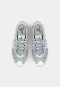 Sive športne čevlje z mrežastim zgornjim delom, belimi akcenti in odbojnimi detajli. Imajo zaobljen prst in oblazinjen podplat. Vidna blagovna znamka.