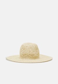 Cappello a tesa larga realizzato in paglia intrecciata, con una corona rotonda e un design ad uncinetto aperto e arioso. Il colore è beige chiaro.