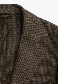 Blazer a cuadros marrones y negros con solapa y bolsillo en el pecho, mostrando una detallada textura de tela de lana y costura a medida.