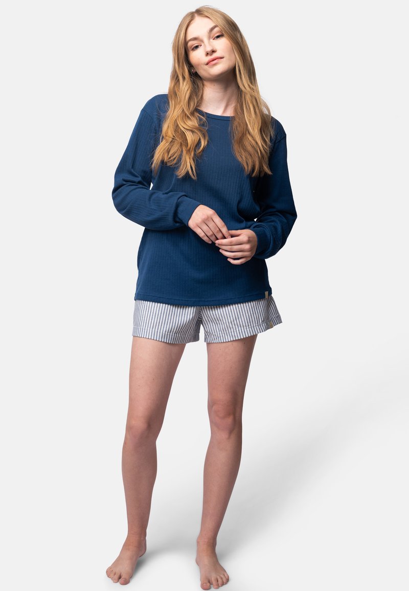 Maglia a maniche lunghe a coste blu navy abbinata a pantaloni corti a righe bianche e blu, con una vestibilità morbida e rilassata. Posizione eretta, a piedi nudi.