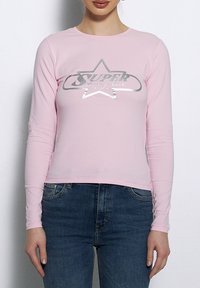 Jasnoróżowa bluzka z długim rękawem z srebrnym wzorem graficznym w kształcie gwiazdy oraz napisem "Super" na przodzie, dopasowany fason, wykonana z mieszanki bawełny.
