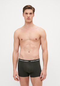 Olivgrüne Boxershorts mit schwarzem Bund, der das weiße "JACK & JONES"-Logo zeigt. Weiches, elastisches Material; figurbetontes Design.