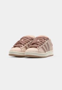 Light pink sneakers made of suede, featuring thick, textured laces, a white midsole, and three contrasting stripes on the side.
