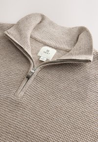 Beige waffle-knit pullover sweater with a ribbed half-zip collar and a "Next" brand label inside the neckline, size medium.