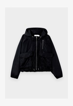 Veste à capuche noire en nylon lisse. Présente une fermeture éclair à l'avant, deux grandes poches avant et des poignets élastiques avec un ourlet à cordon.