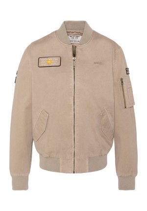 Blouson aviateur beige avec fermeture éclair frontale, poignets et ourlet côtelés, deux poches latérales, et une poche zippée sur la manche gauche avec des écussons sur la poitrine et la manche.