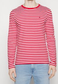 Rød og hvidstribet langærmet T-shirt med rund halsudskæring, lavet af blødt bomuld, med et lille logo på brystet.