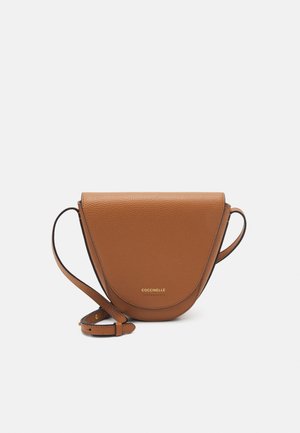 Sac bandoulière en cuir marron avec un rabat incurvé et une sangle réglable, avec le nom de la marque "Coccinelle" en lettres dorées.
