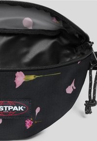 Svart dragkedjefodral med rosa blommönster, textilstruktur och synlig märkesetikett. Insidan har en slät, ljusfodrad.