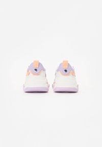Baskets blanches avec des accents pastel violets et pêches. Matériau synthétique lisse, bout rond et semelle en caoutchouc violet clair. Anse à l'arrière.