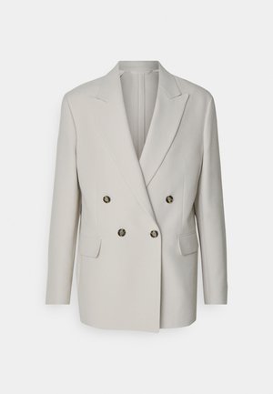 Blazer beige clair à double boutonnage avec poignées en pointe, deux poches avant et boutons ronds foncés. Tissu lisse, coupe ajustée.